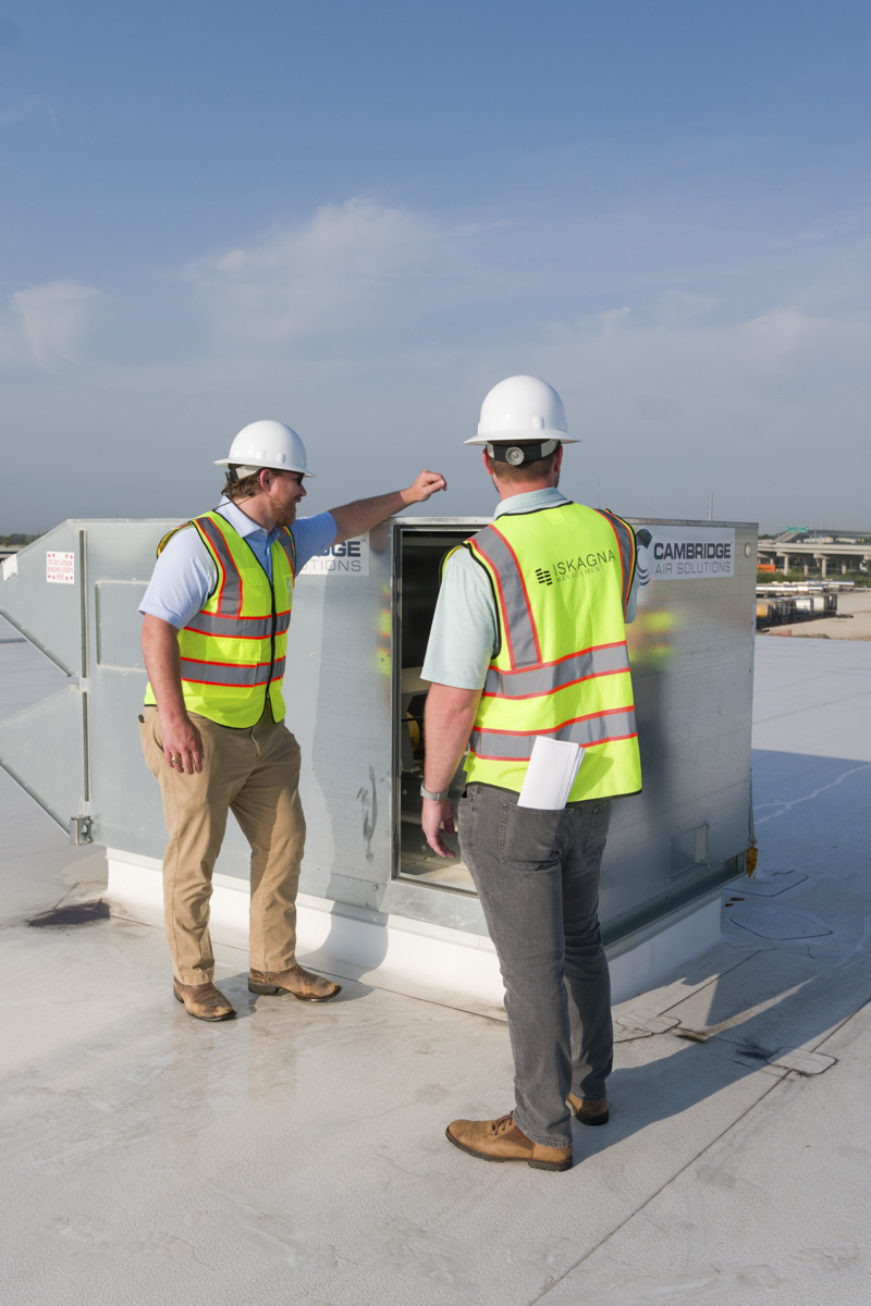 Aerial photo of three team members reviewing plans and referring to the computer